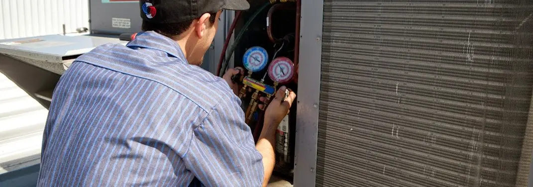 HVAC technician servicing a condenser unit in Bogalusa